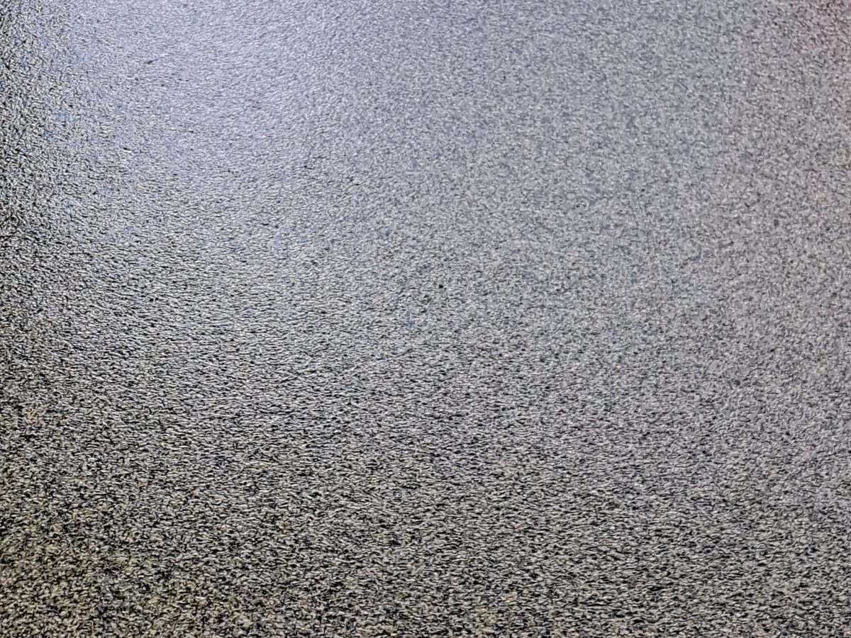 Gray flake close-up — full broadcast chip on a 100% solids polyurea basecoat. This is what the finished surface actually looks like up close.