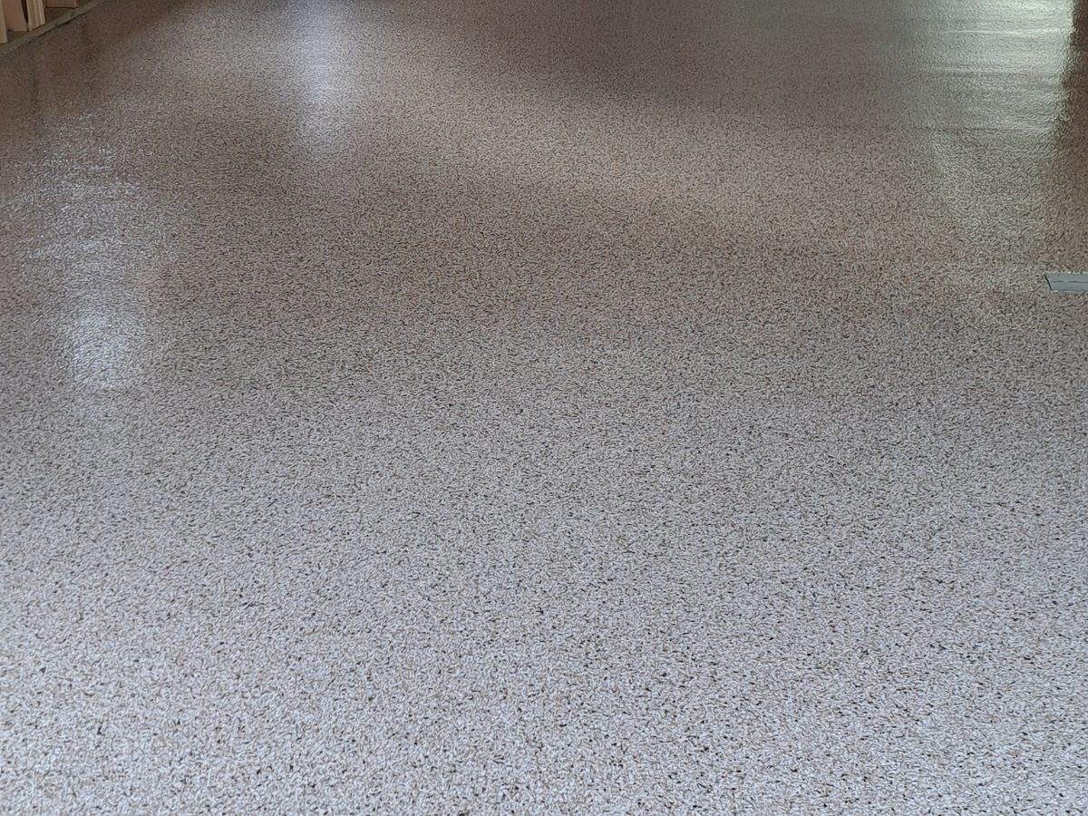 Warm tan flake broadcast — tight chip density on a workshop floor, slip-resistant and seamless.